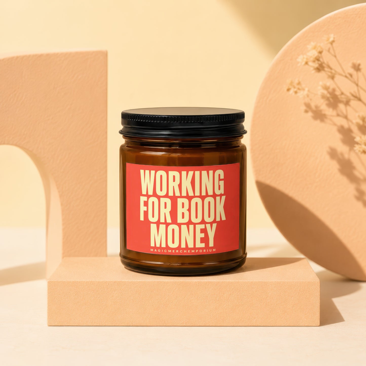 Amber jar candle with red label that reads "WORKING FOR BOOK MONEY".