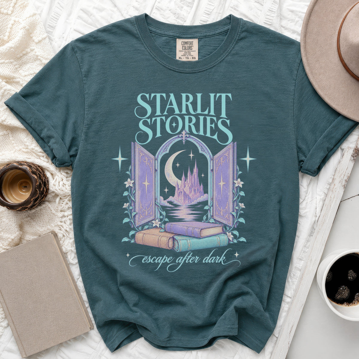 Teal t-shirt with "Starlit Stories" and a castle behind an arch, plus "escape after dark".