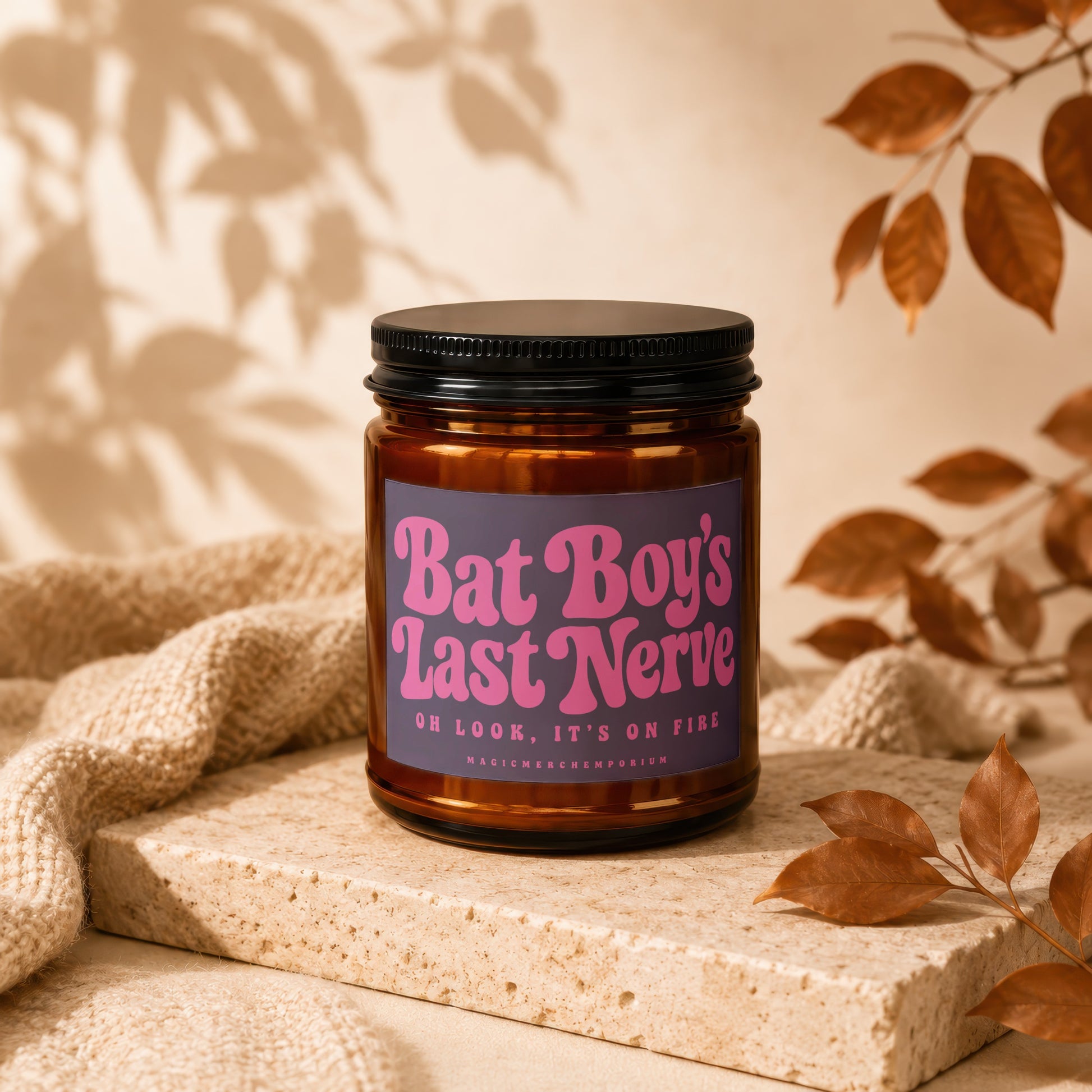 Amber candle jar with purple label reading "Bat Boy's Last Nerve. Oh Look, It's On Fire".