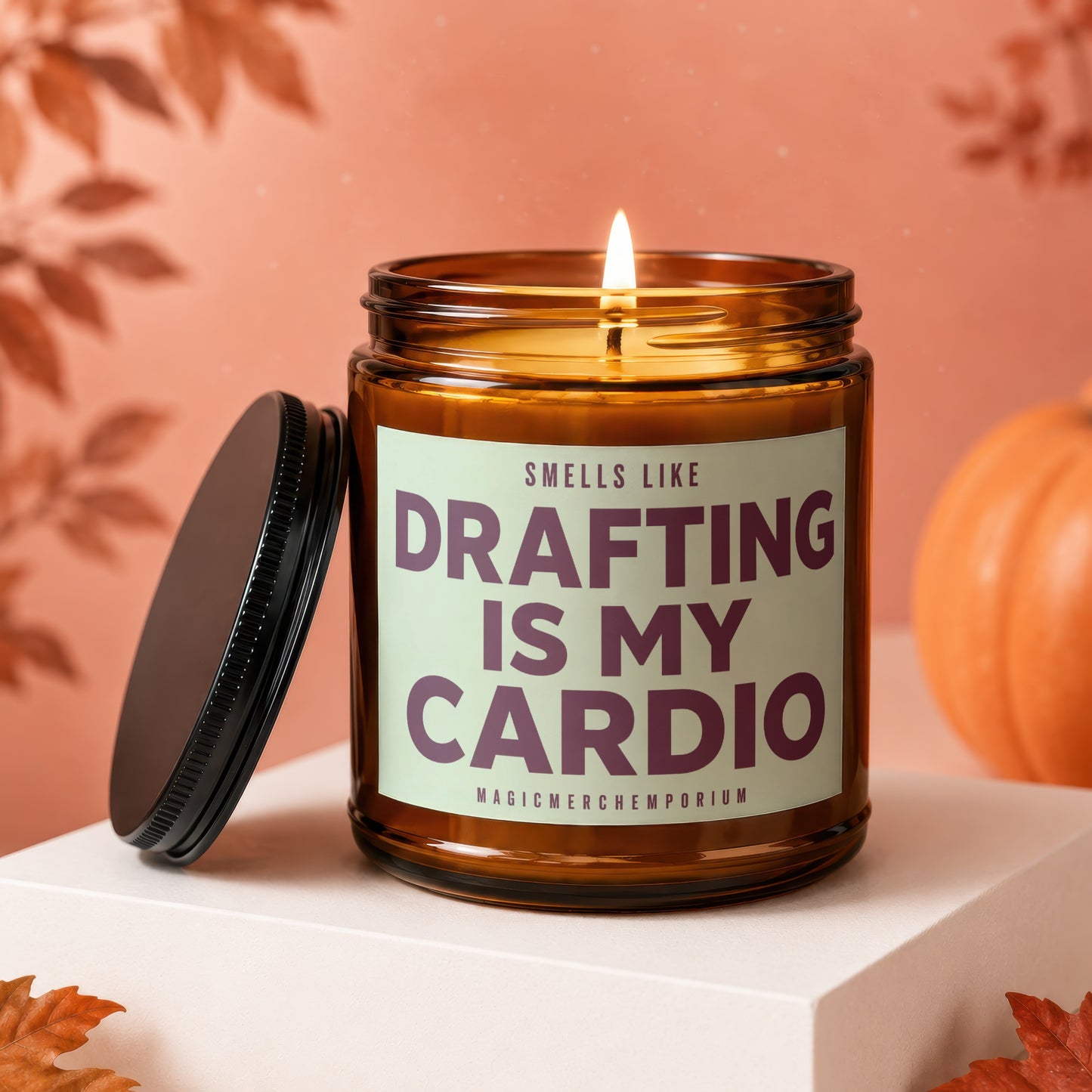 Amber jar candle with lit wick, reads "Smells like drafting is my cardio."