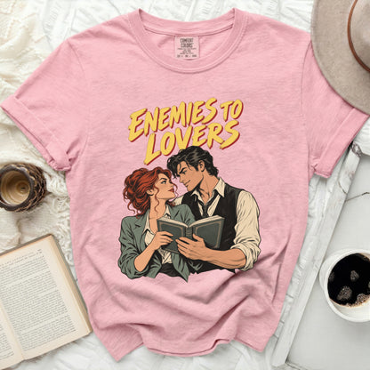 Pink t-shirt with "Enemies to Lovers" graphic of a couple reading a book.