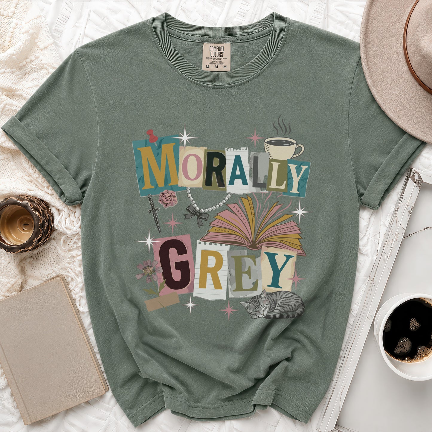 Green t-shirt with "Morally Grey" text, open book, sword, rose, pearls, and cat graphic.