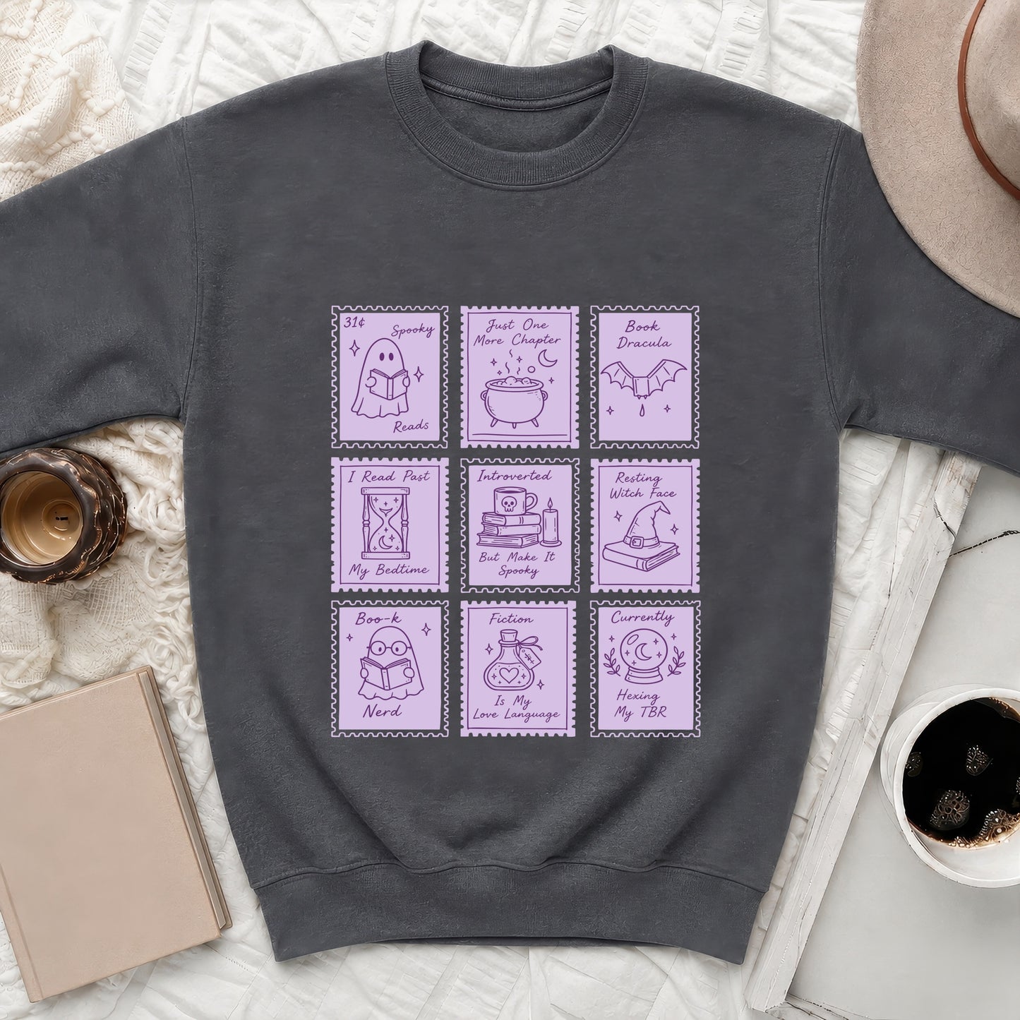 Dark grey sweatshirt with a nine-panel design of ghost, cauldron, bat, and book illustrations.