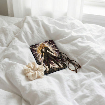 Book with stained glass woman, scrunchie, and glasses on white sheets