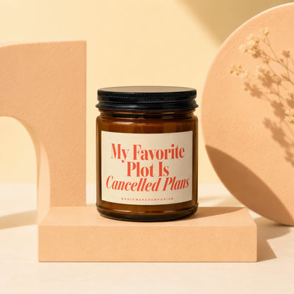 Amber jar candle with black lid and label reading "My Favorite Plot Is Cancelled Plans".