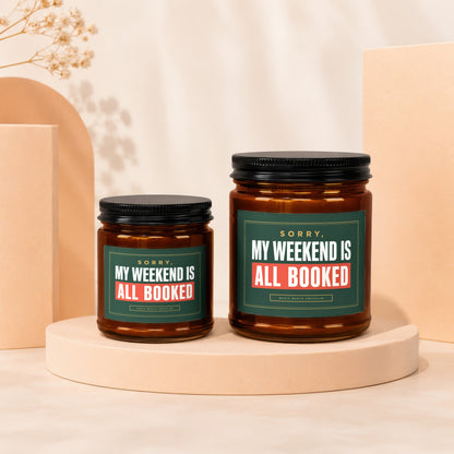 Two amber candles with "My Weekend Is All Booked" text on green labels.