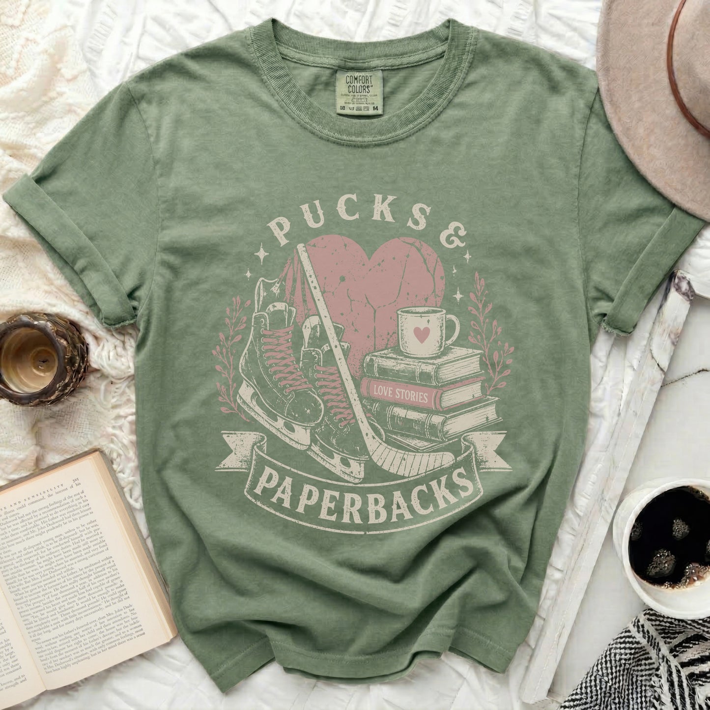 Green t-shirt with "Pucks & Paperbacks" text, hockey skates, heart, books, and coffee cup.