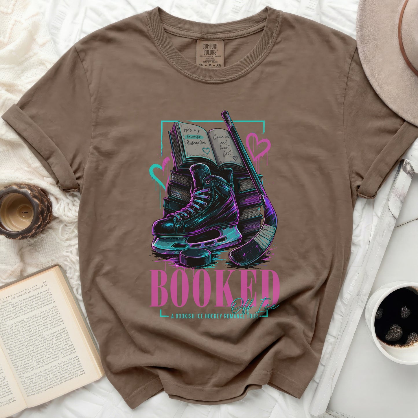 T-shirt with graphic of books, ice skates, and hockey stick with text "Booked"