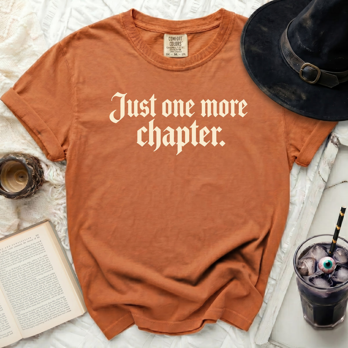 Orange t-shirt with "Just one more chapter." text and witch hat.