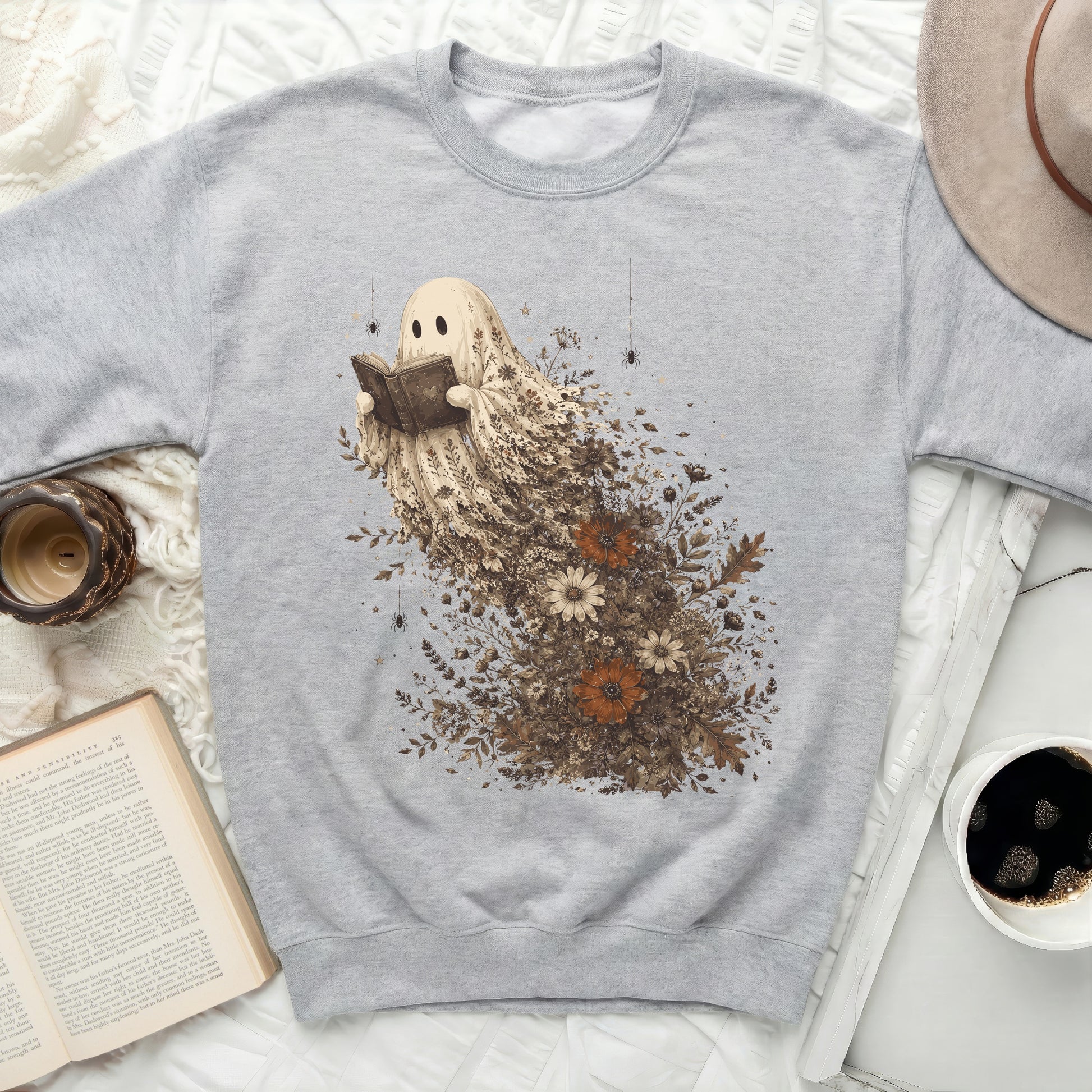 Graphic sweatshirt with a ghost reading a book surrounded by floral elements.