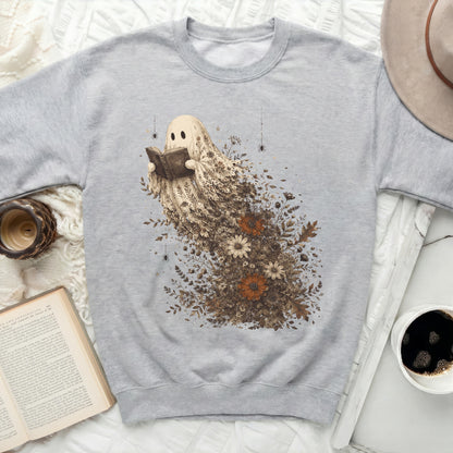 Graphic sweatshirt with a ghost reading a book surrounded by floral elements.