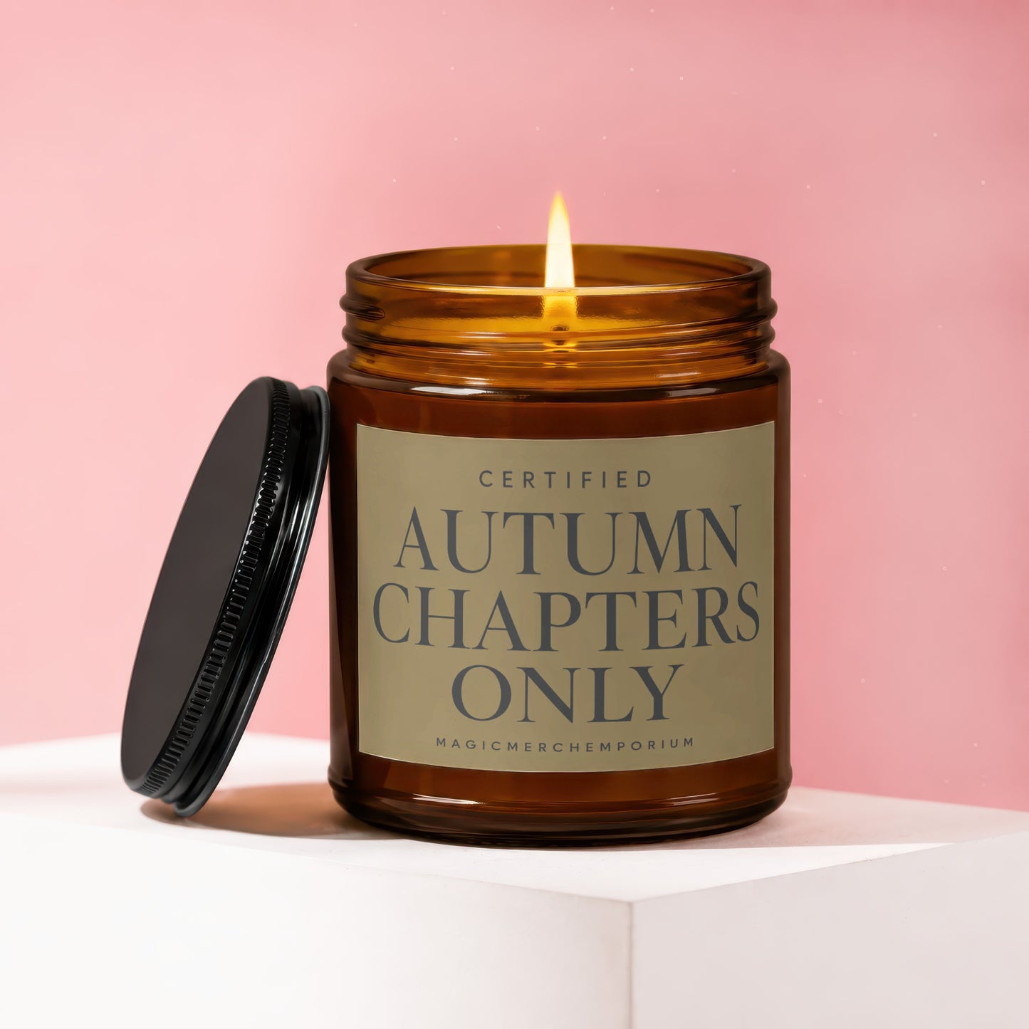 Amber jar candle with lit flame, lid off, reading: CERTIFIED AUTUMN CHAPTERS ONLY.