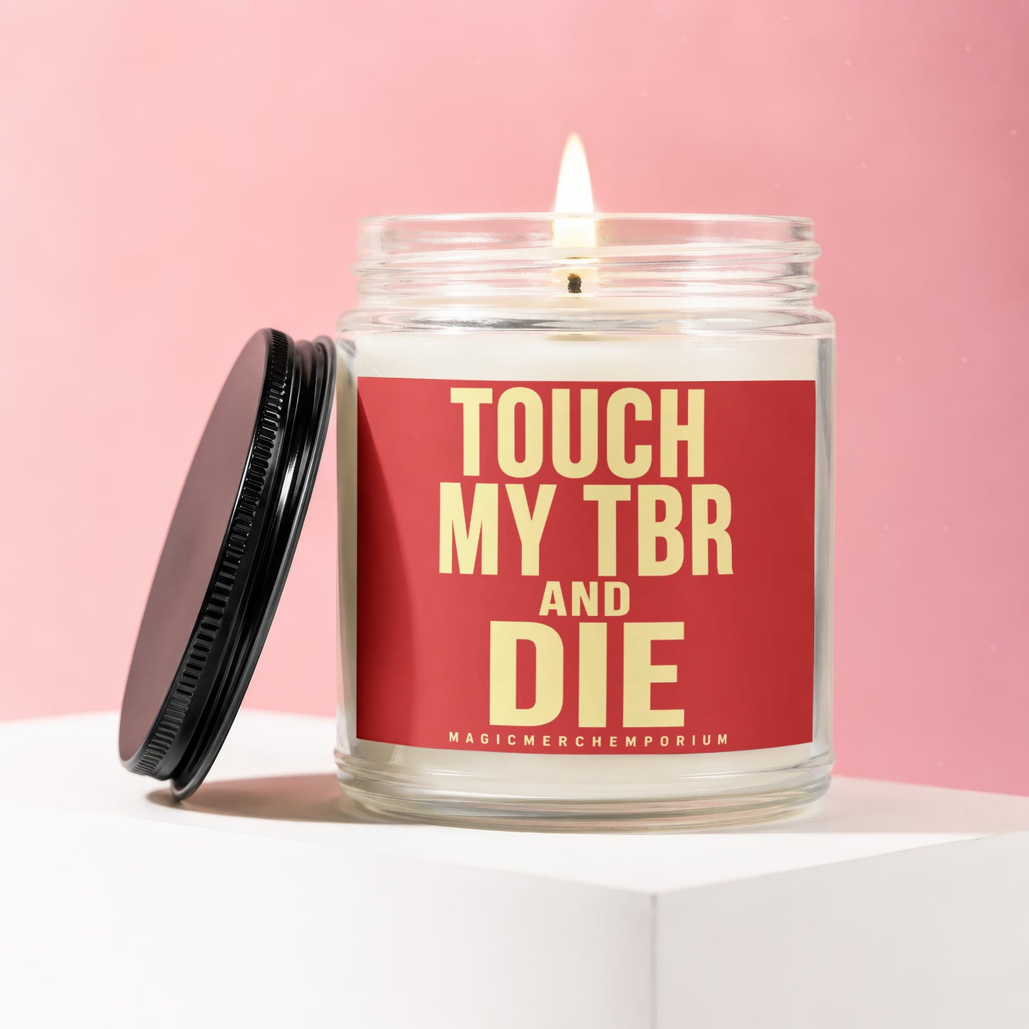 Glass jar candle with lit wick and red label reading "TOUCH MY TBR AND DIE"