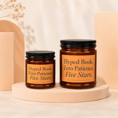 Two amber glass candles with black lids and orange labels reading "Hyped Book. Zero Patience. Five Stars."