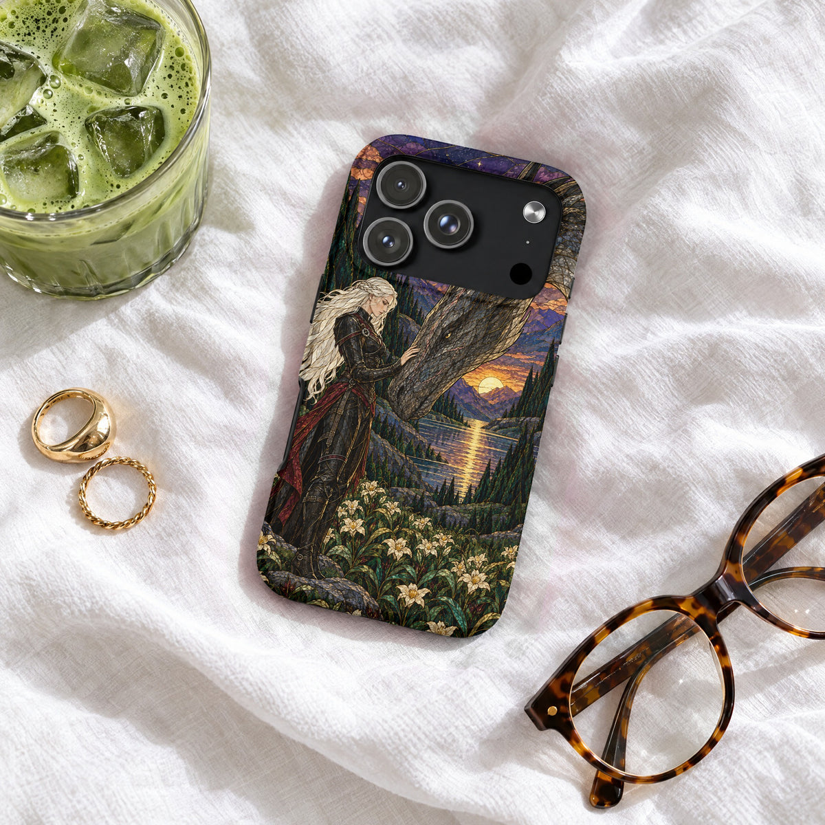 An iPhone case featuring fantasy art of a blonde woman touching a dragon near a lake at sunset.