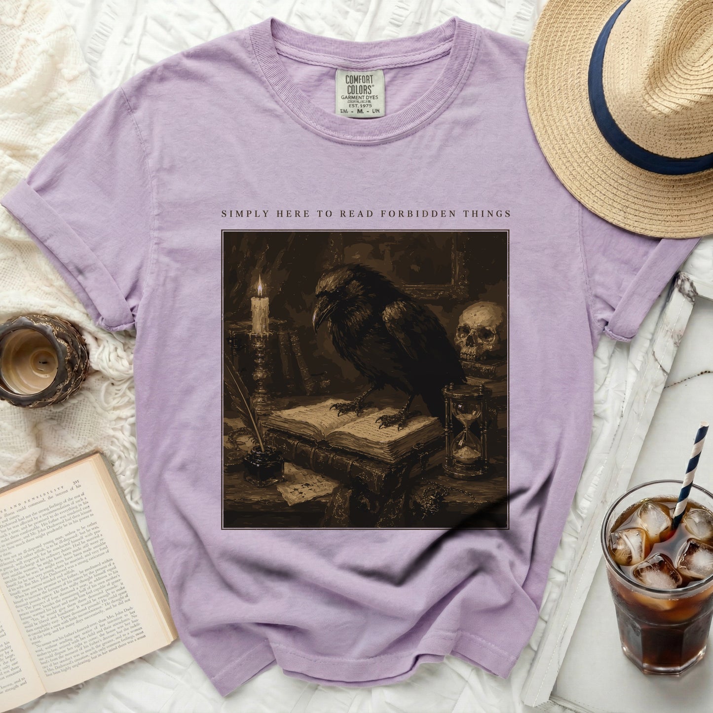 Purple t-shirt with raven on books and text "SIMPLY HERE TO READ FORBIDDEN THINGS"