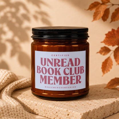 Amber jar candle with "Certified Unread Book Club Member" text and "MagicMerchEmporium" logo.