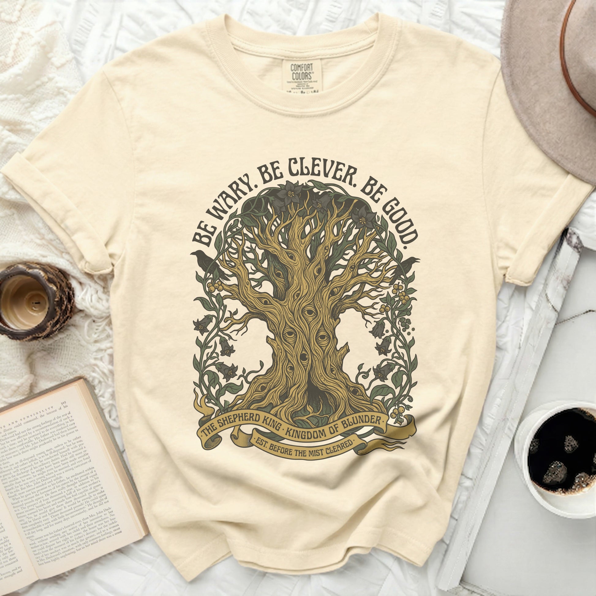 Cream t-shirt with tree graphic and "Be Wary. Be Clever. Be Good." text.