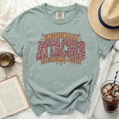 Light blue t-shirt with "Emotionally Attached to Fictional People" leopard print text.