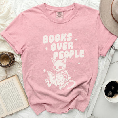 Pink t-shirt with a skeleton cat reading a book and text "Books Over People."