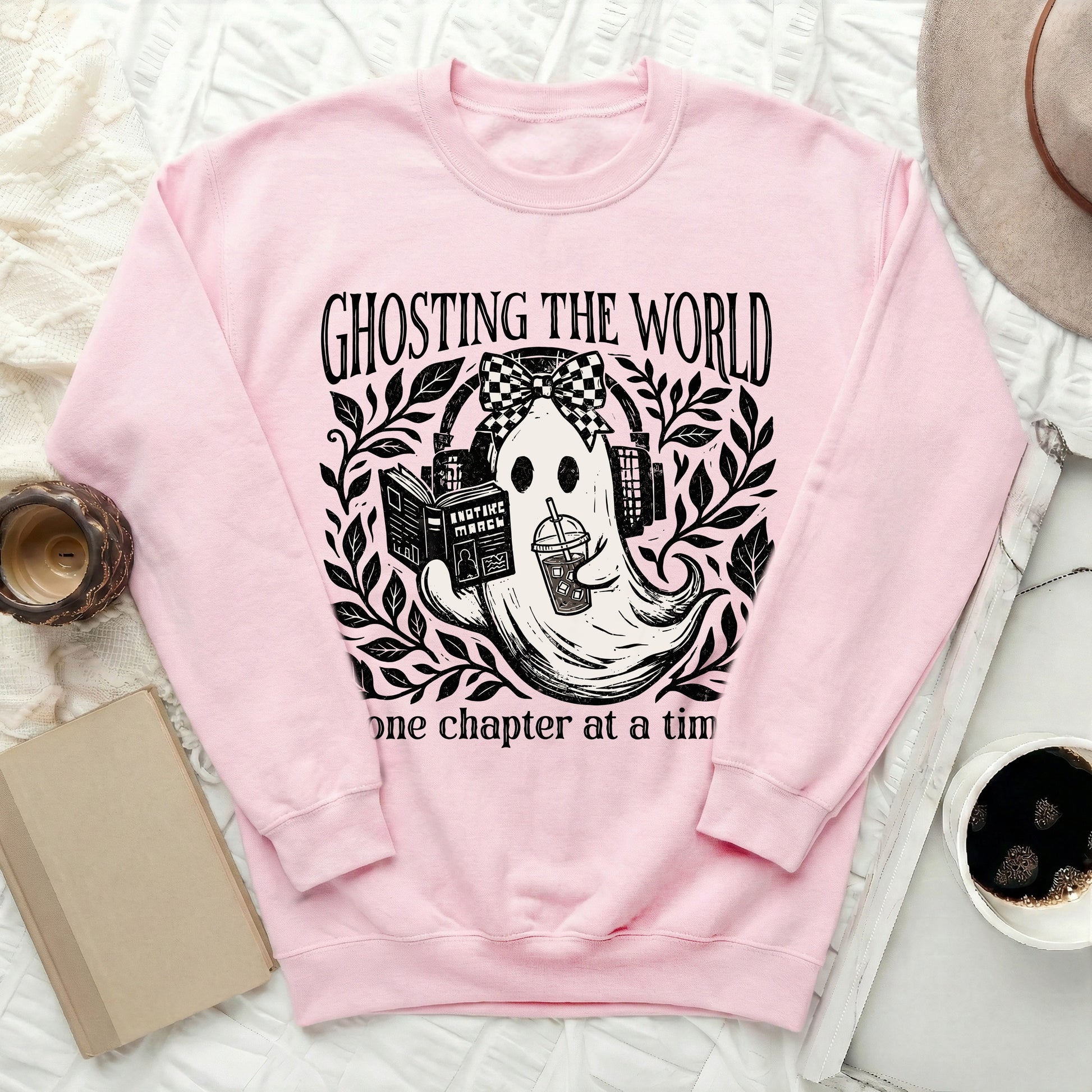Pink sweatshirt with ghost reading a book and drinking coffee. "Ghosting the world one chapter at a time" text.