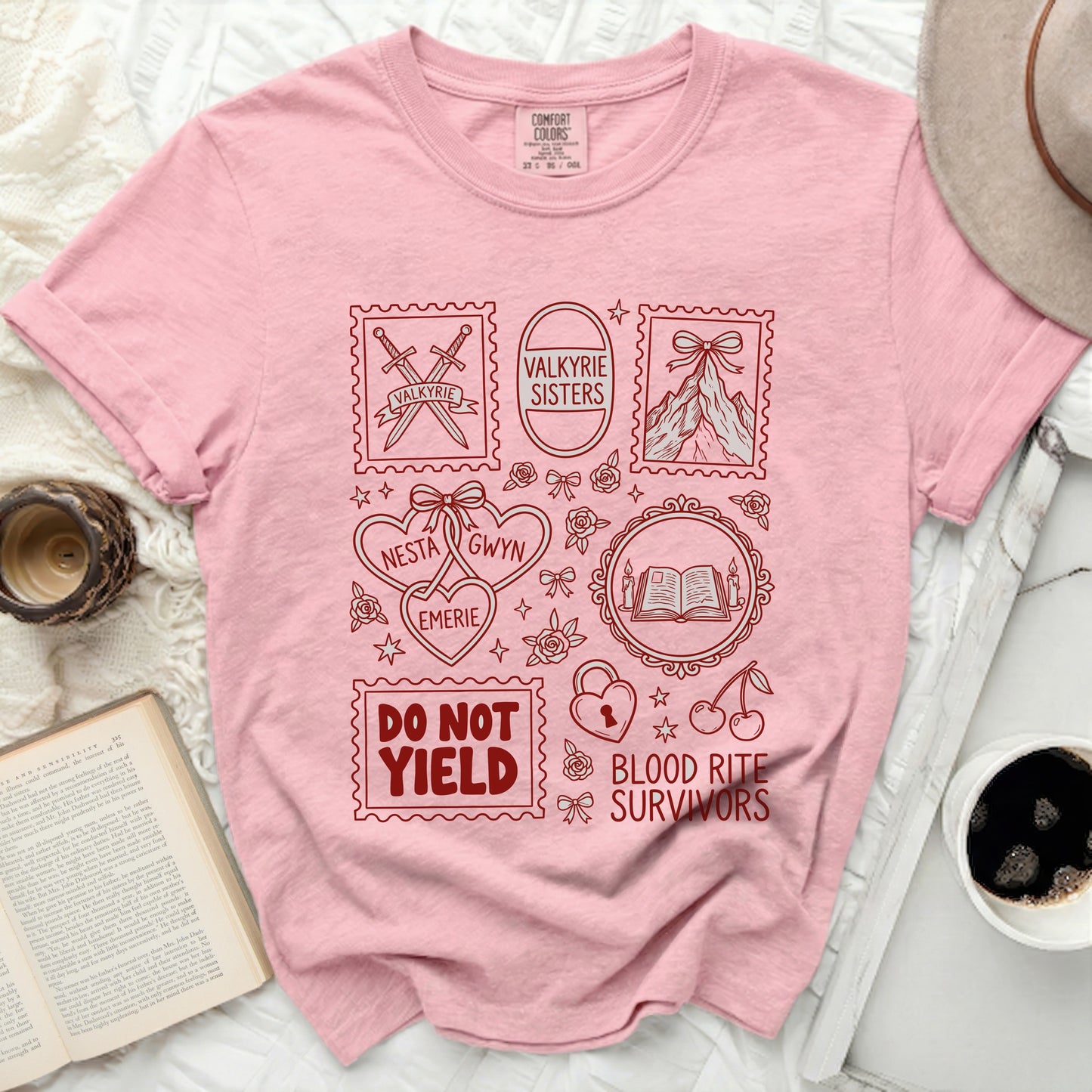 Pink t-shirt with red graphic stamps featuring swords, mountains, hearts, and text: "Valkyrie Sisters", "Nesta", "Gwyn", "Emerie", "Do Not Yield", "Blood Rite Survivors".