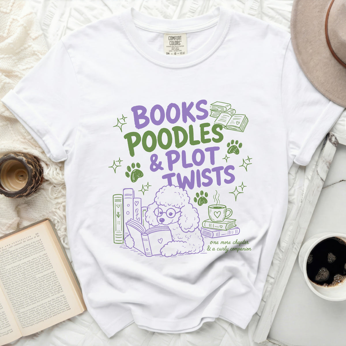 White t-shirt with purple and green graphic: "BOOKS POODLES & PLOT TWISTS".