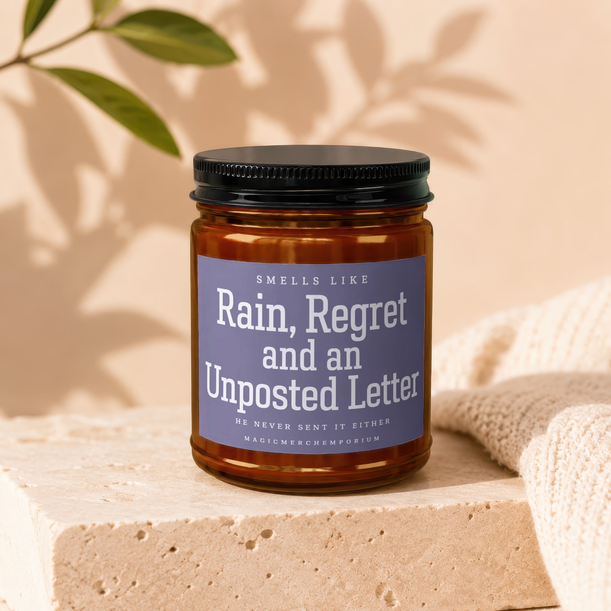 Amber jar candle with purple label reading "Rain, Regret and an Unposted Letter."