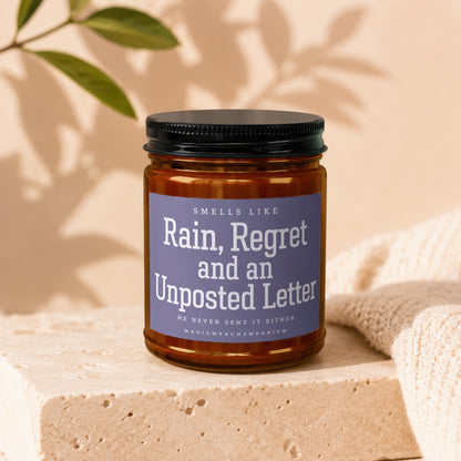 Amber jar candle with purple label reading "Rain, Regret and an Unposted Letter."