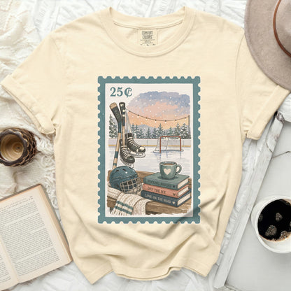 T-shirt with postage stamp design of hockey scene, skates, and books.