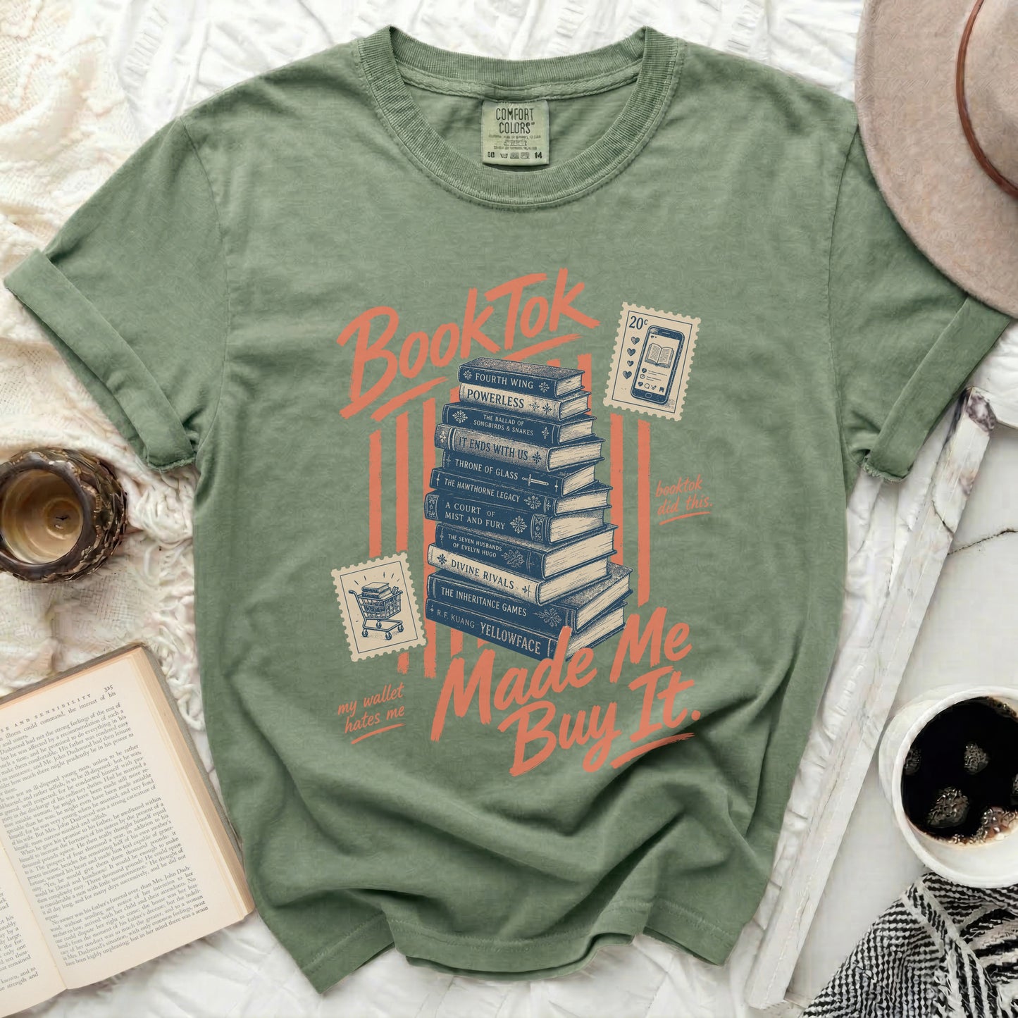 T-shirt with "BookTok made me buy it" slogan over stack of books.