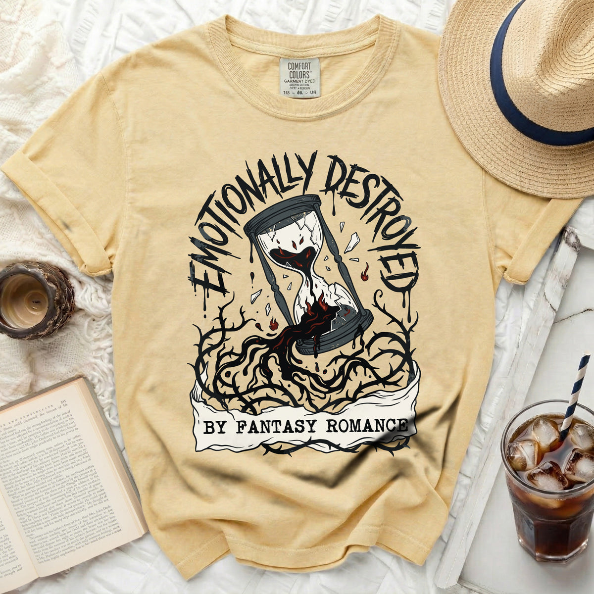 Yellow t-shirt with a graphic of a broken hourglass and thorns, text reads "Emotionally Destroyed by Fantasy Romance".