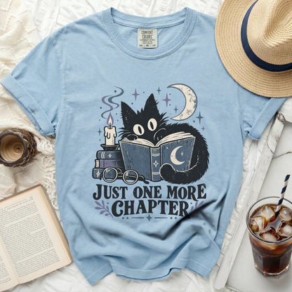 Light blue t-shirt with black cat reading and "Just One More Chapter" text.