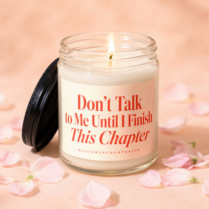 Glass candle with lit wick and lid, reading "Don't Talk to Me Until I Finish This Chapter."