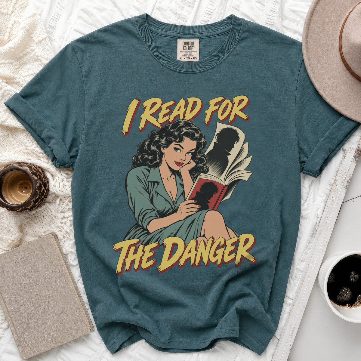 Teal t-shirt with comic-style graphic of woman reading, "I READ FOR THE DANGER" text.
