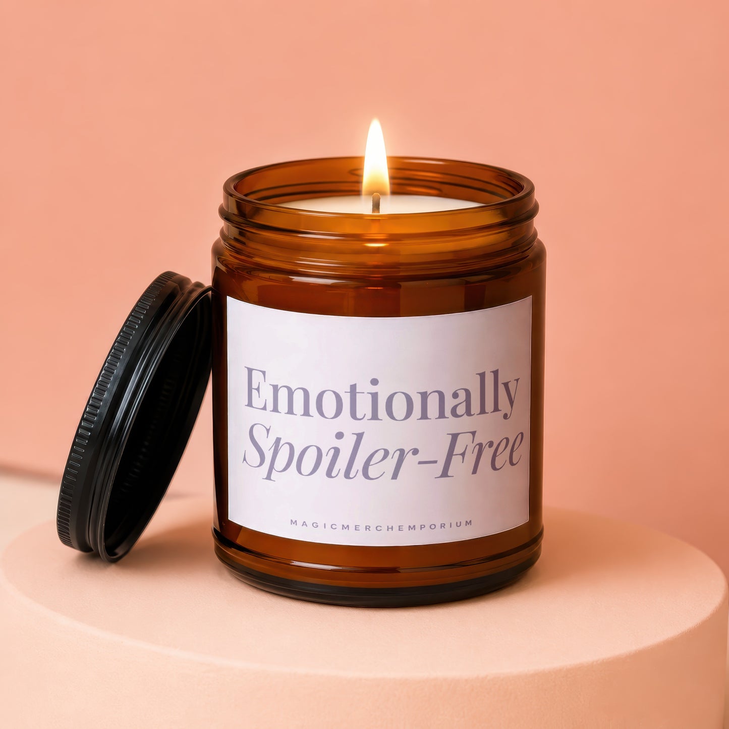 Lit candle in amber glass jar with lid off, label reads "Emotionally Spoiler-Free".