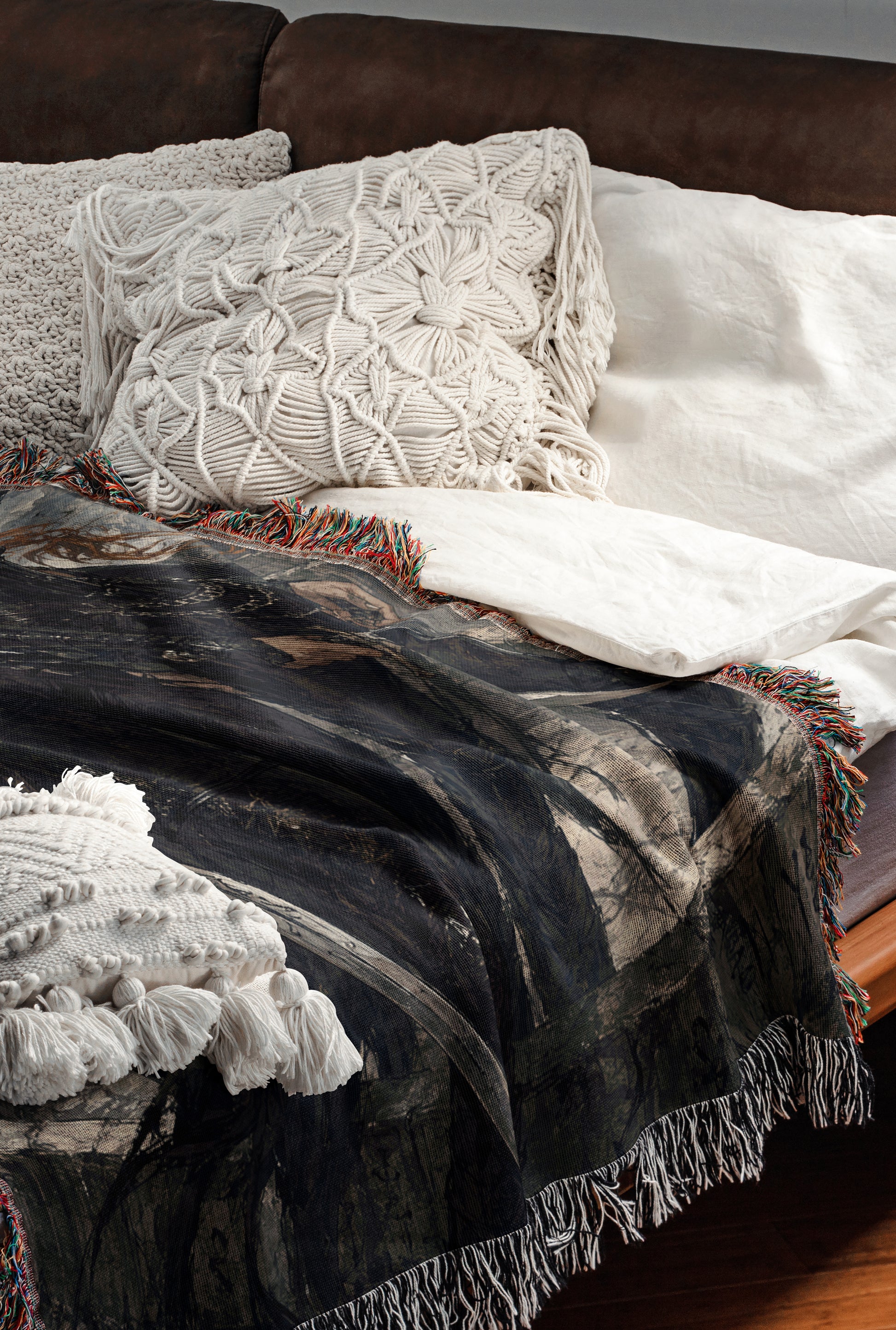 a cozy and inviting bedroom scene, featuring a bed with a black and white patterned blanket and a white pillow. The bed is set against a brown leather couch, creating a warm and comfortable atmosphere.