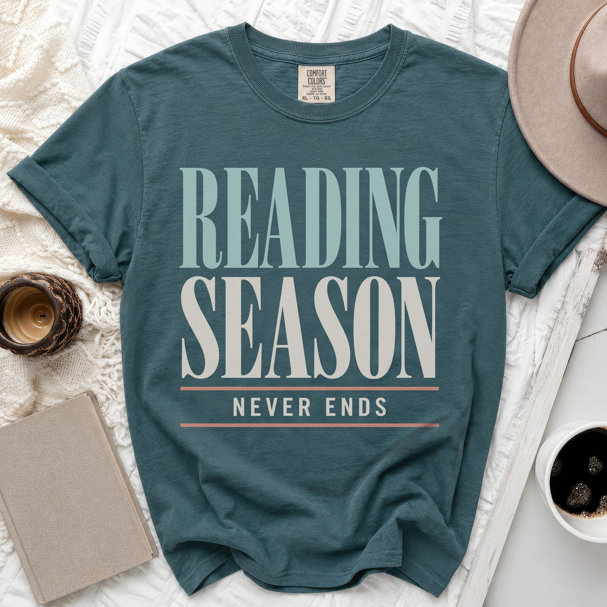 Teal t-shirt with "Reading Season Never Ends" text in cream and light blue.