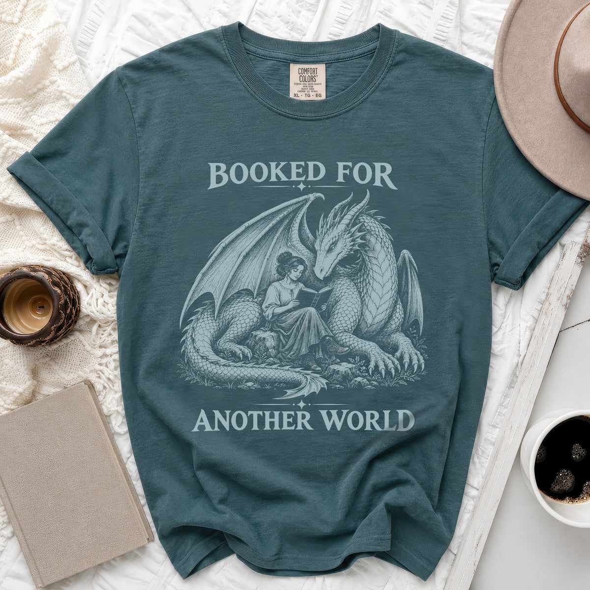 T-shirt with dragon and woman reading, text "Booked for Another World".
