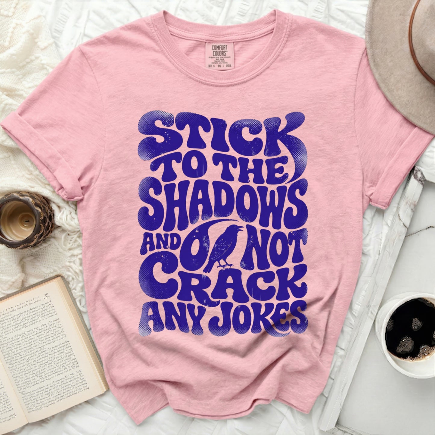 Pink t-shirt with blue retro text: "STICK TO THE SHADOWS AND DO NOT CRACK ANY JOKES."