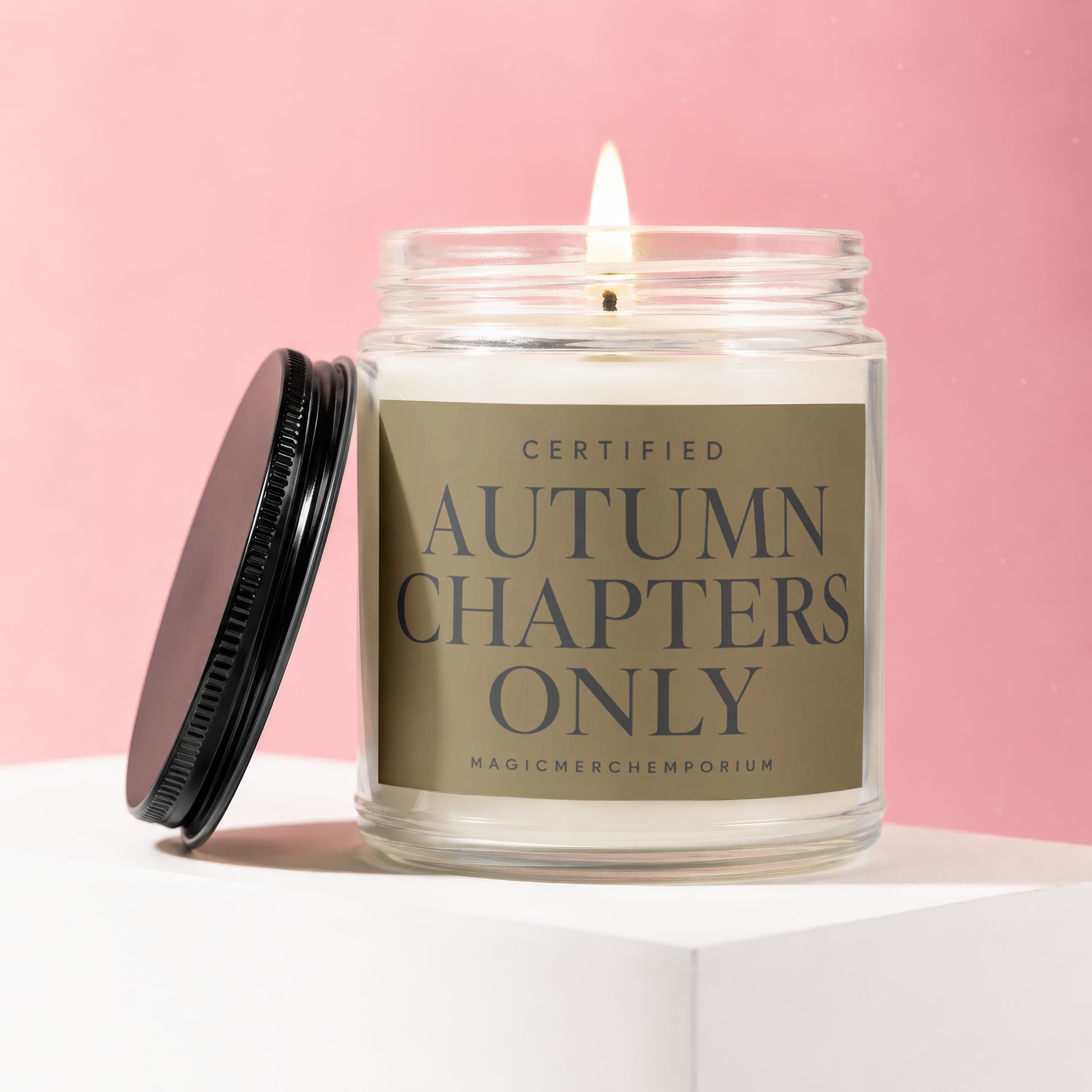 Lit glass jar candle with black lid beside it, labeled "Certified Autumn Chapters Only".