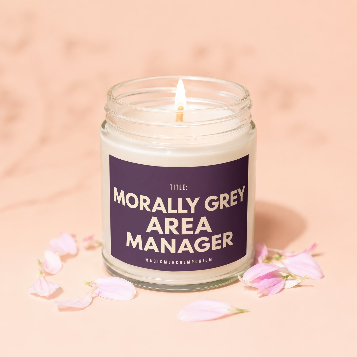 Morally Grey Area Manager candle with lit wick and petals, on a peach background.