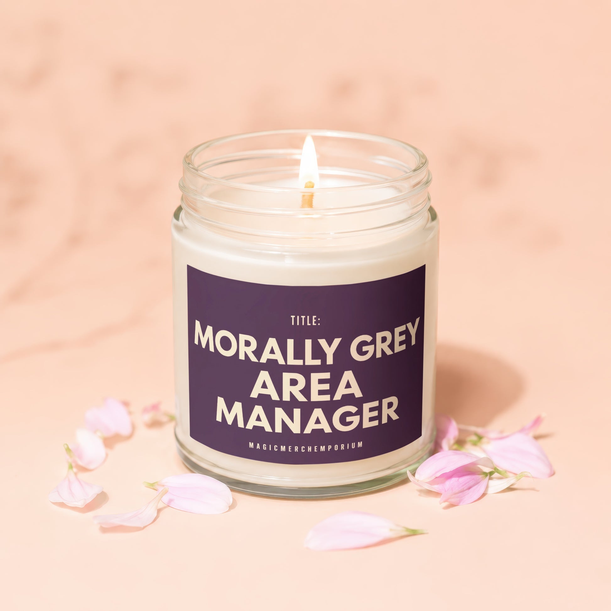Morally Grey Area Manager candle with lit wick and petals, on a peach background.