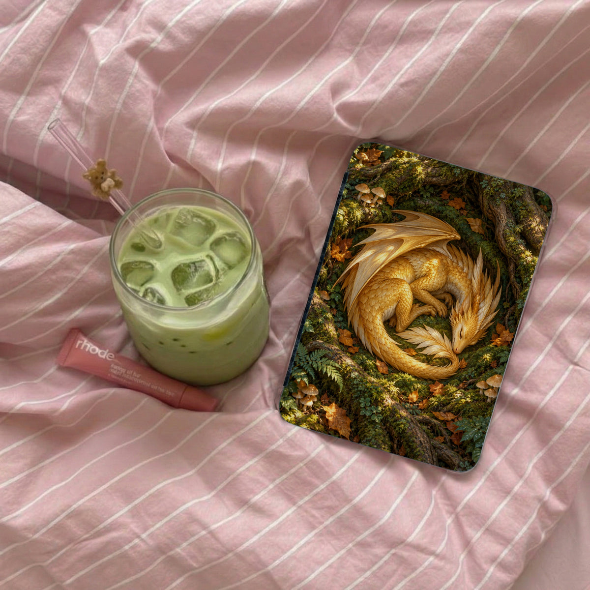 A golden dragon sleeps coiled on a mossy forest floor next to a green drink.