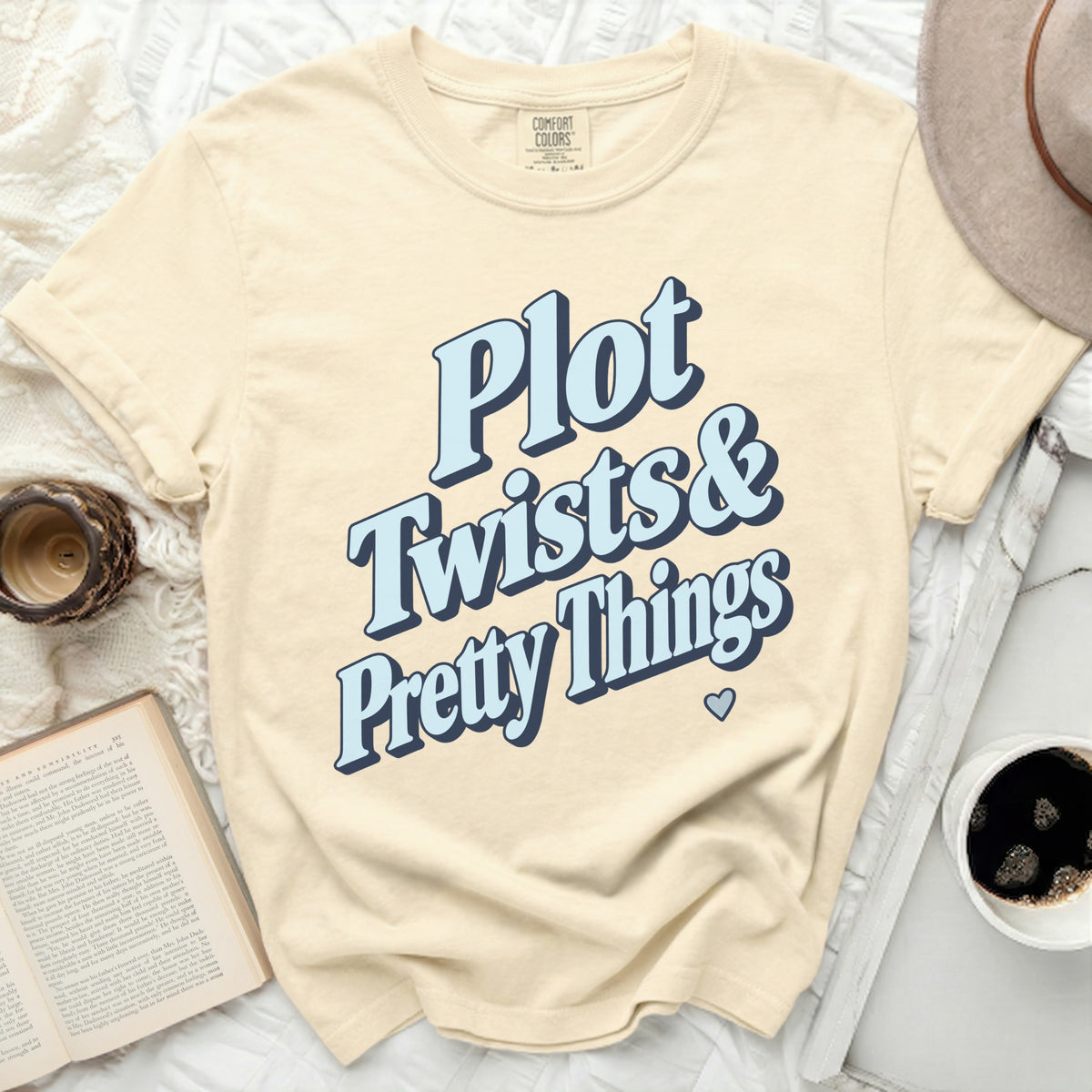 Cream t-shirt with "Plot Twists & Pretty Things" text in blue and navy.