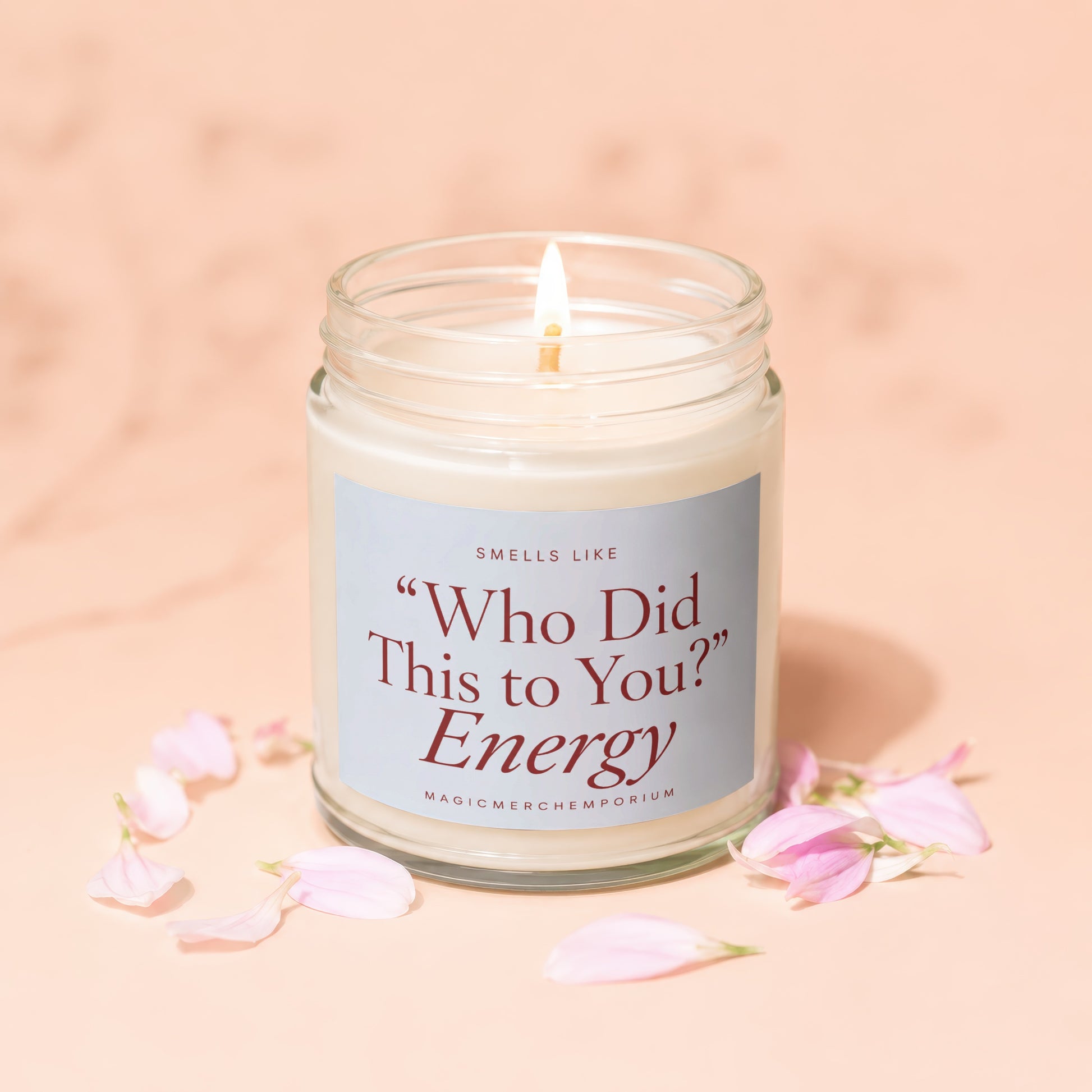 Lit candle in a glass jar with "Who Did This to You? Energy" on the label.