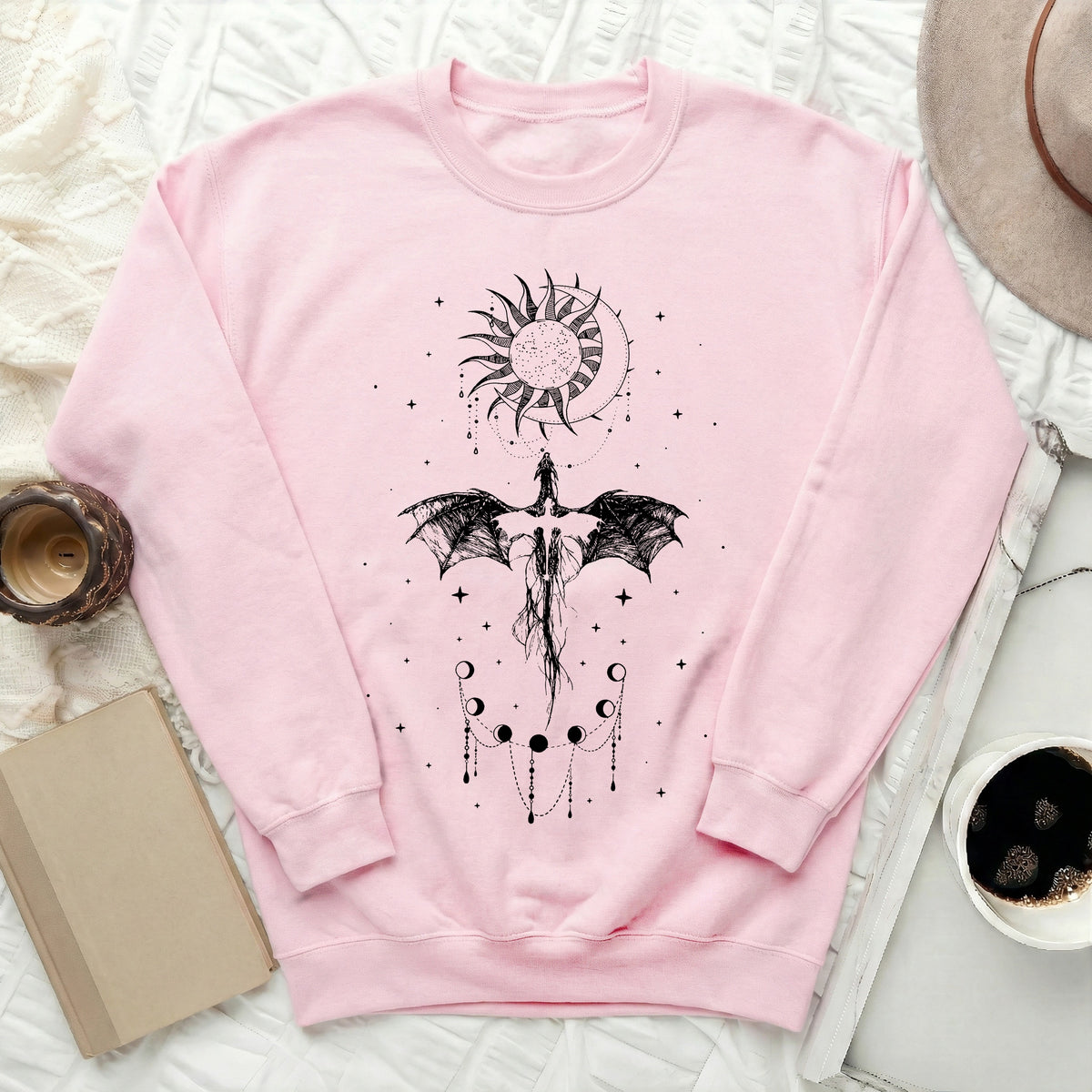 Light pink crewneck sweatshirt featuring a black graphic of a dragon, sun, moon, and stars.