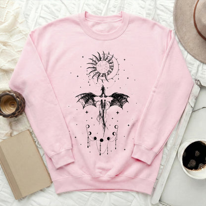 Light pink crewneck sweatshirt featuring a black graphic of a dragon, sun, moon, and stars.