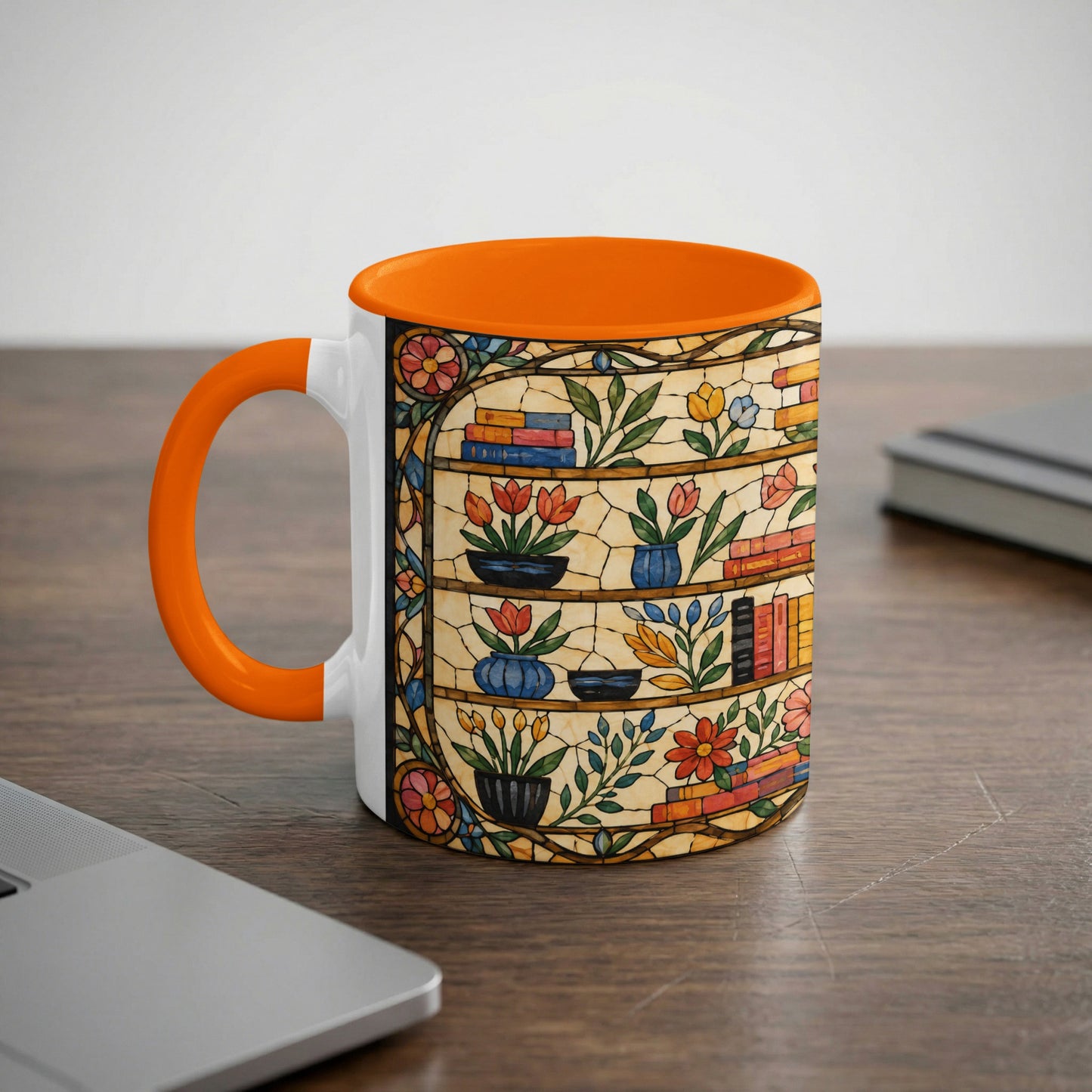 White mug with orange handle featuring a stained-glass design of bookshelves and flowers.