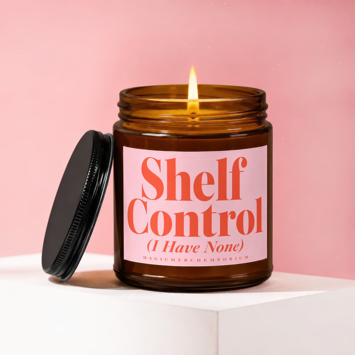 Amber jar candle with lit flame and black lid, reading "Shelf Control".